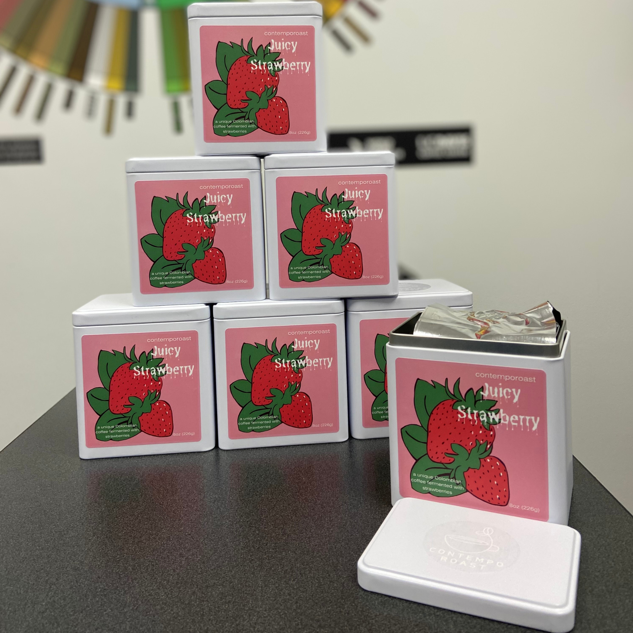 A small stack of 8-ounce matte white tins with Juicy Strawberry coffee labels