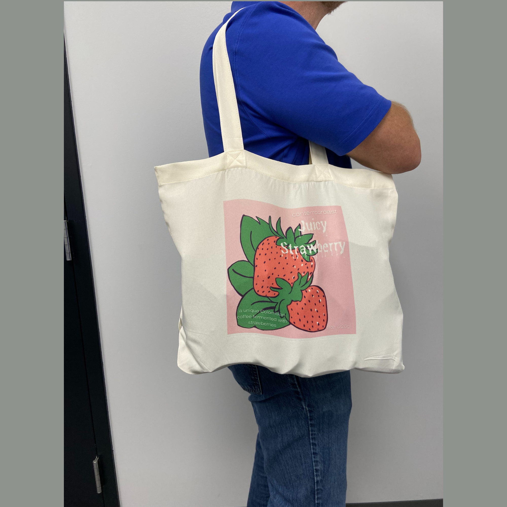 Man holding an off-white Juicy Strawberry tote bag on his shoulder