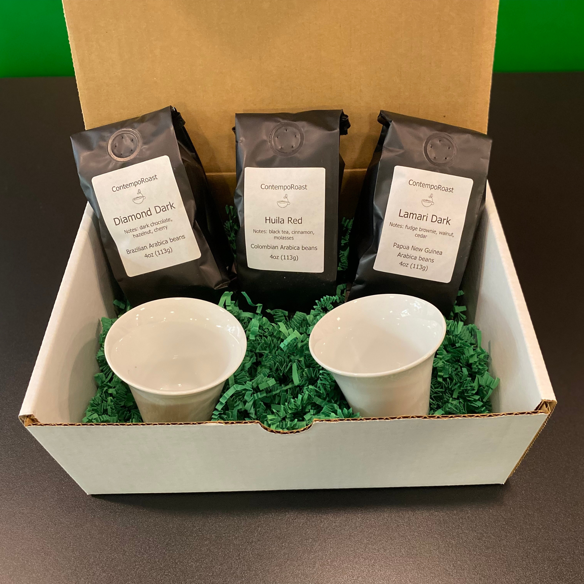 Our darker set: 2 notNeutral Cala 3-oz tasting cups with a 4-oz bag each of Esmeralda, Haitian Blue and Tropical Tolima whole-bean coffee bags; shown inside the gift box