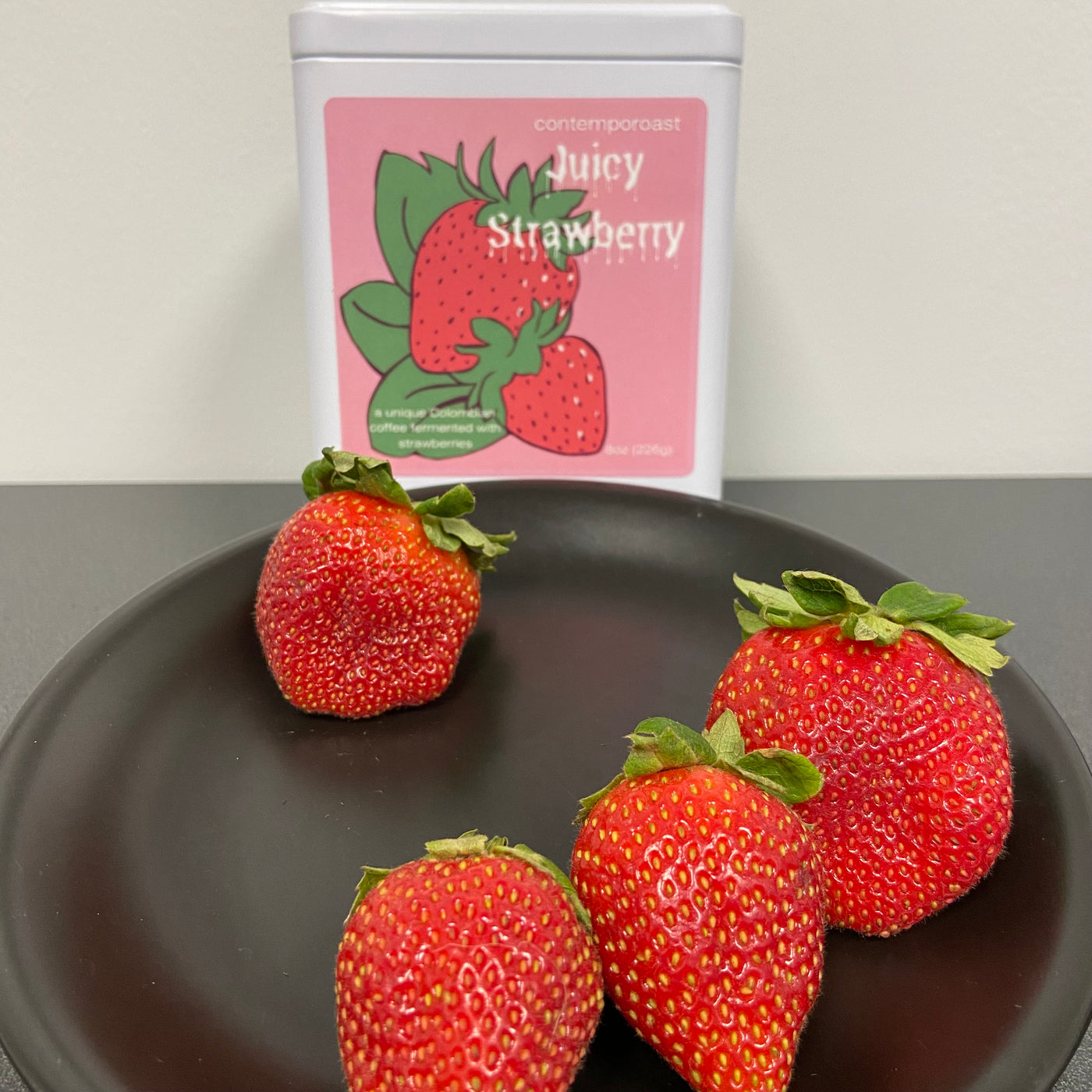 Plate of fresh strawberries with keepsake tin of 8oz Juicy Strawberry coffee in the background