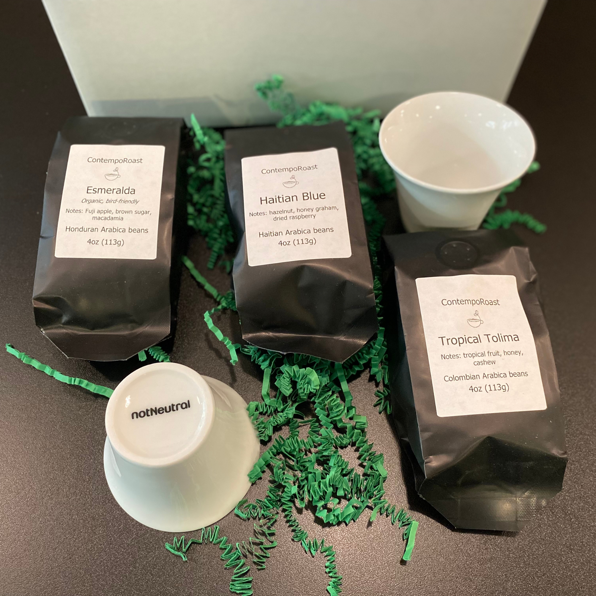 Our lighter set: 2 notNeutral Cala 3-oz tasting cups with a 4-oz bag each of Esmeralda, Haitian Blue and Tropical Tolima whole-bean coffee bags; shown sitting outside the gift box